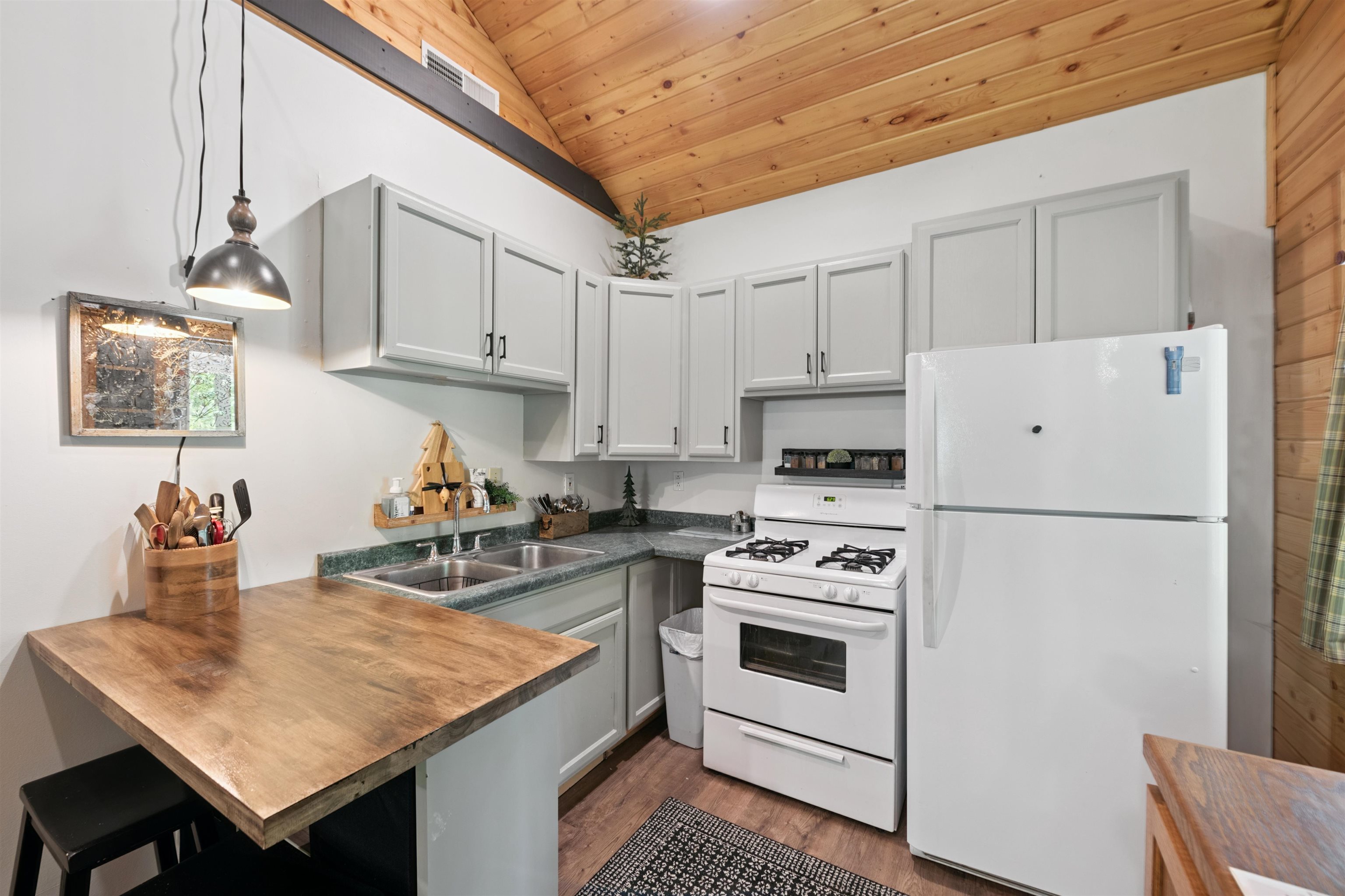 Kitchen with white appliances, vaulted ceiling, a peninsula, wood ceiling, and dark wood-type flooring
