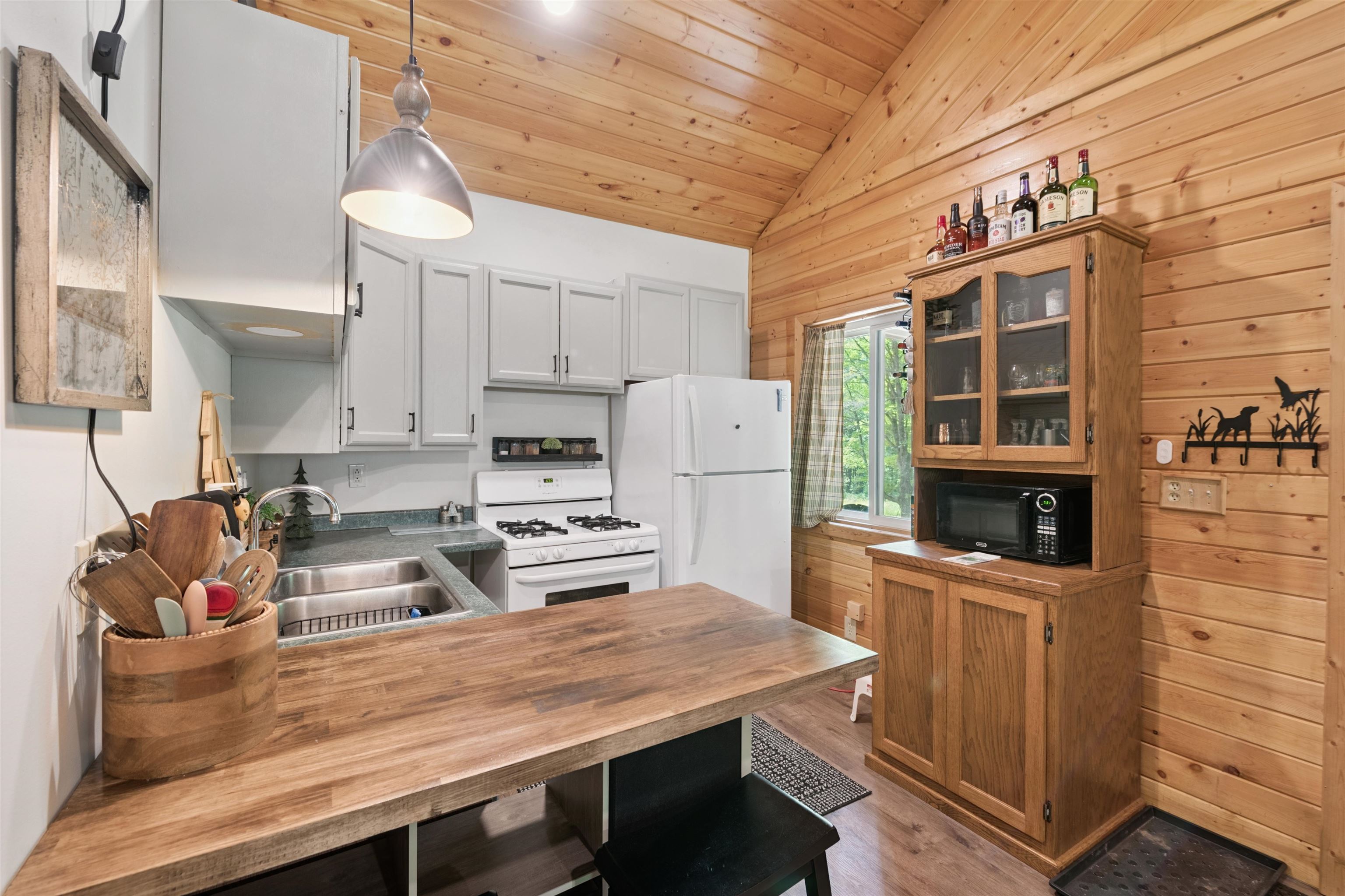 Kitchen featuring lofted ceiling, white appliances, butcher block countertops, glass insert cabinets, and wood finished floors