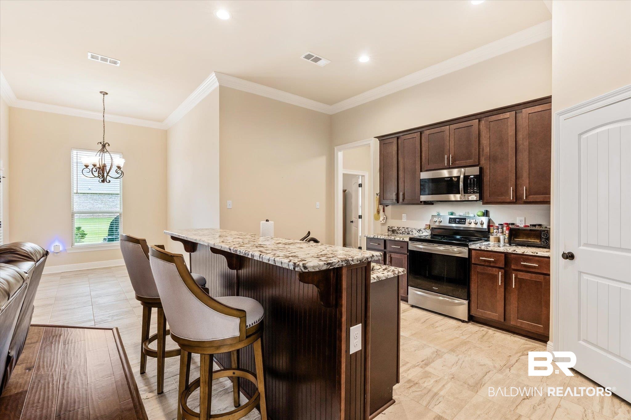 1786 Vivace Drive Foley, AL 36535 - Photo 8 of 21 Kitchen featuring dark brown cabinets, a breakfast bar, appliances with stainless steel finishes, light stone countertops, and a center island