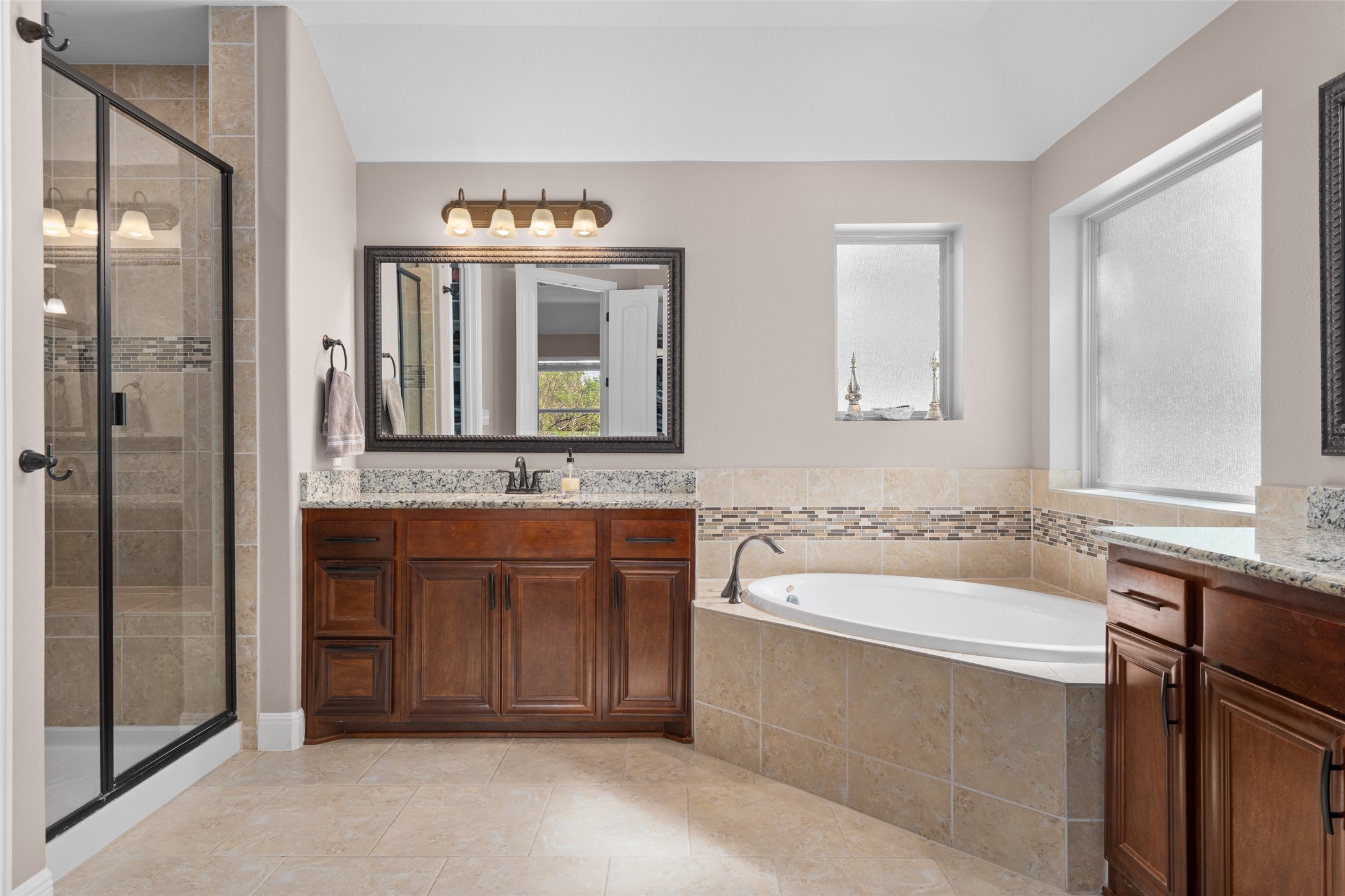 164 Milestone Road Liberty Hill, TX 78642 - Photo 18 of 40 Full bathroom with a garden tub, a large shower, two vanities, and two walk in closets.