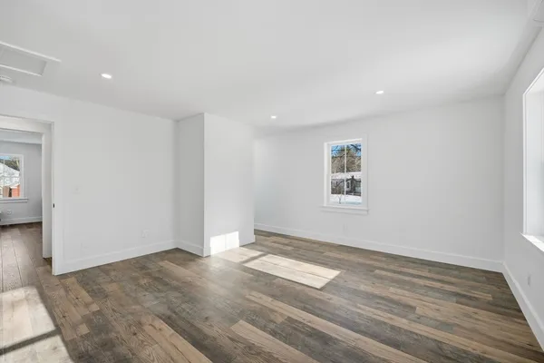 an empty room with wooden floor and windows
