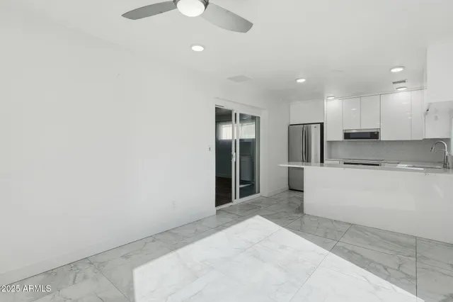 a large white kitchen with kitchen island a sink stainless steel appliances and cabinets