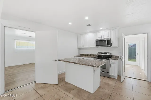 a kitchen with stainless steel appliances granite countertop a refrigerator and a stove top oven