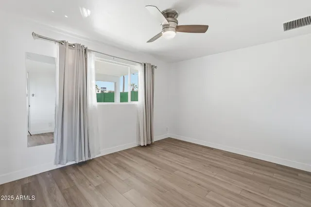 a view of empty room with wooden floor and fan