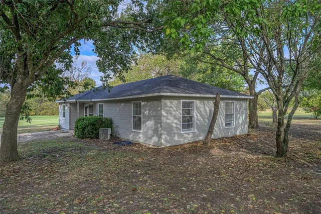 a view of a house with large trees and a yard