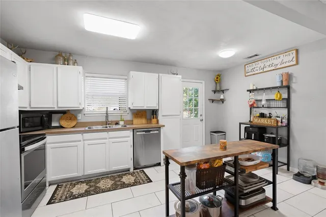 a kitchen with stainless steel appliances a dining table chairs refrigerator and sink