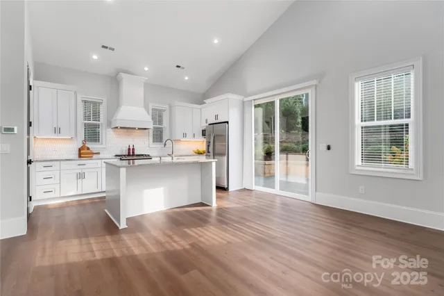 a kitchen with stainless steel appliances granite countertop a refrigerator sink and white cabinets