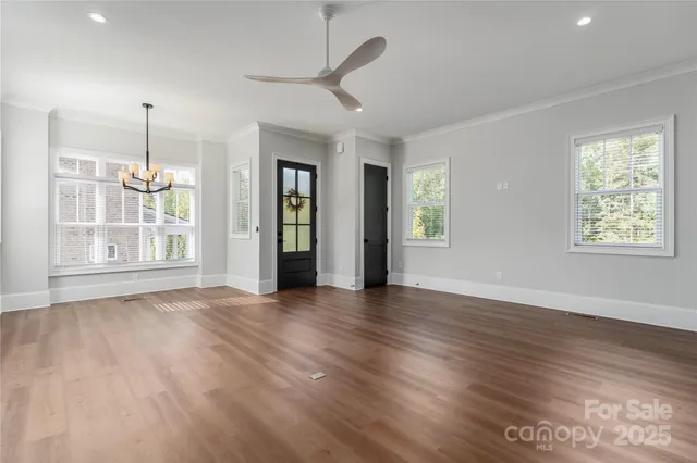 a view of an empty room with window and wooden floor