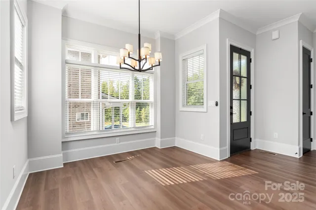 an empty room with wooden floor cabinet and windows