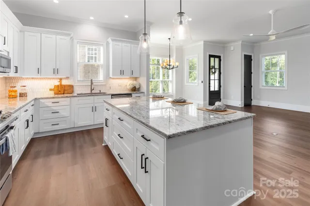 a large kitchen with granite countertop a large counter top space appliances and cabinets