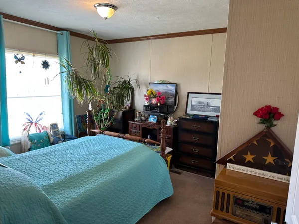 a bedroom with a bed and a flat tv screen on the dresser