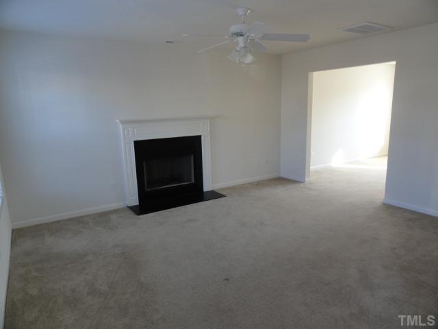 3441 Ferdilah Lane Raleigh, NC 27610 - Photo 2 of 12 an empty room with a fireplace and fan