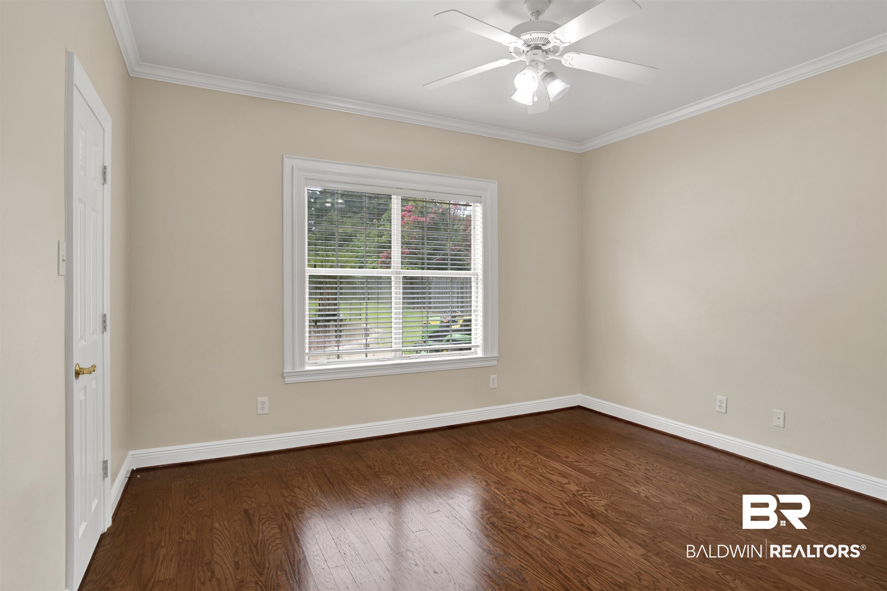 8847 Dawes Lake Road South Mobile, AL 36619 - Photo 16 of 47 Spacious room featuring wood-finish flooring, a white trim window, a ceiling fan with integrated lighting, crown molding, and a paneled door
