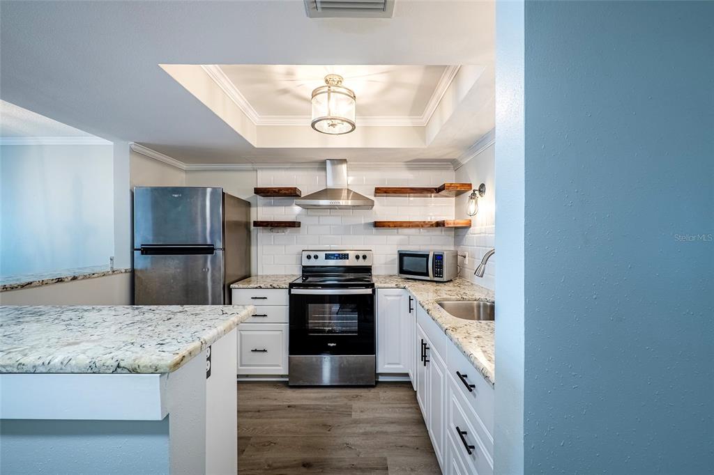 620 Edgewater Drive, Unit 103 Dunedin, FL 34698 - Photo 5 of 26 a kitchen with stainless steel appliances granite countertop a stove and cabinets