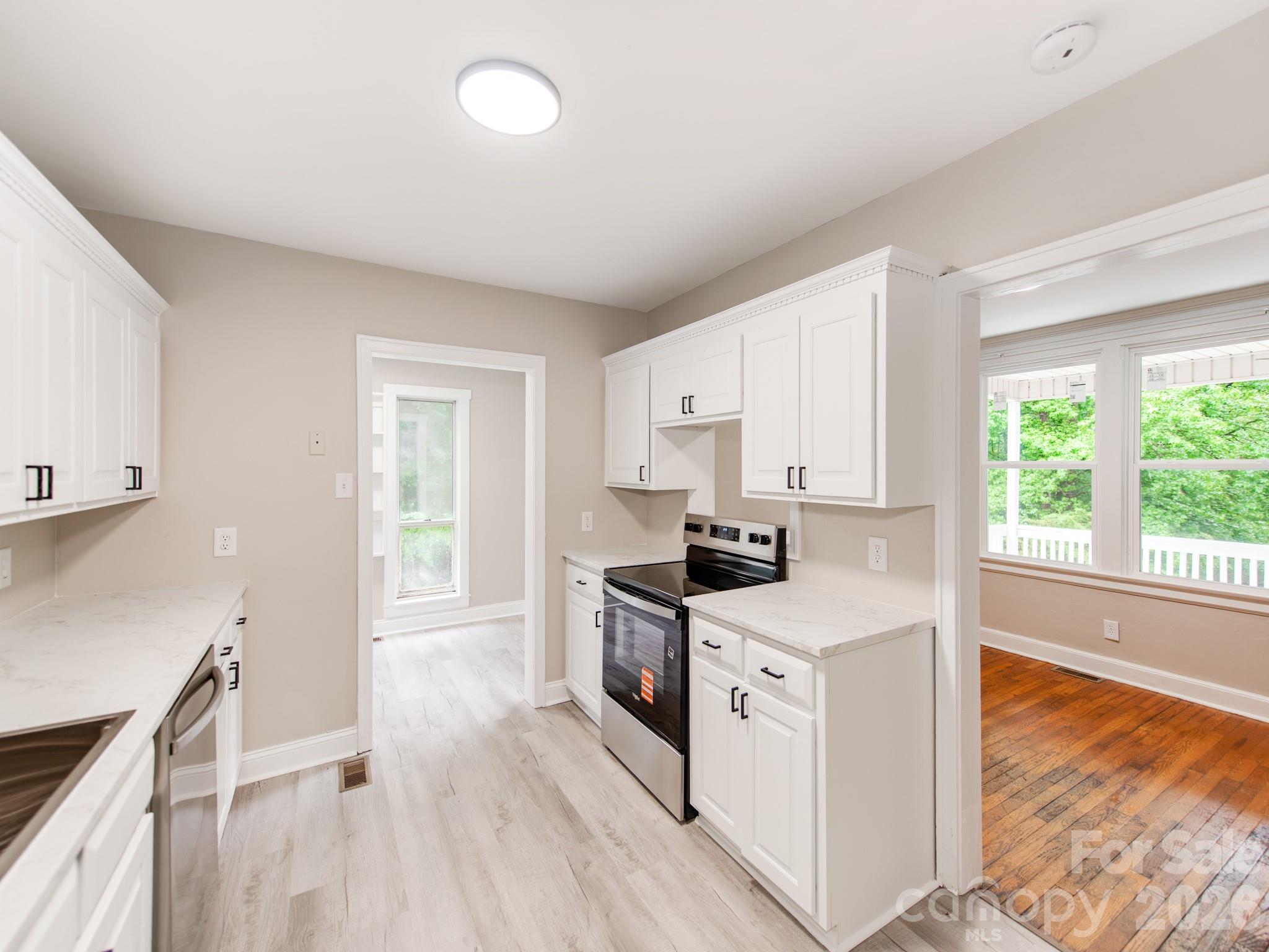 4699 Cherrystone Road Lancaster, SC 29720 - Photo 11 of 28 a kitchen with stainless steel appliances granite countertop a stove a sink and white cabinets with wooden floor
