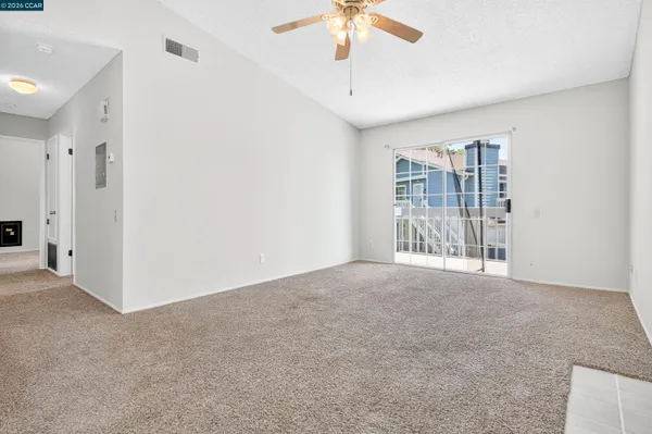 a view of an empty room with chandelier fan and fire place