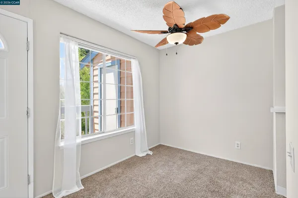 an empty room with a window and a fan