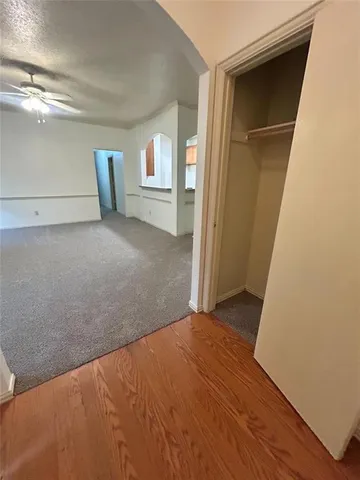 a view of empty room with wooden floor and fan