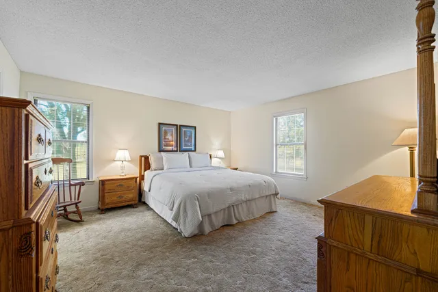 a spacious bedroom with a bed and a dresser with rug