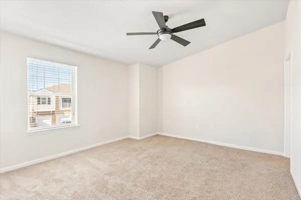 an empty room with a window and a fan