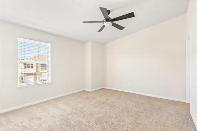 an empty room with a window and a fan