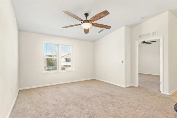 an empty room and chandelier fan in hallway