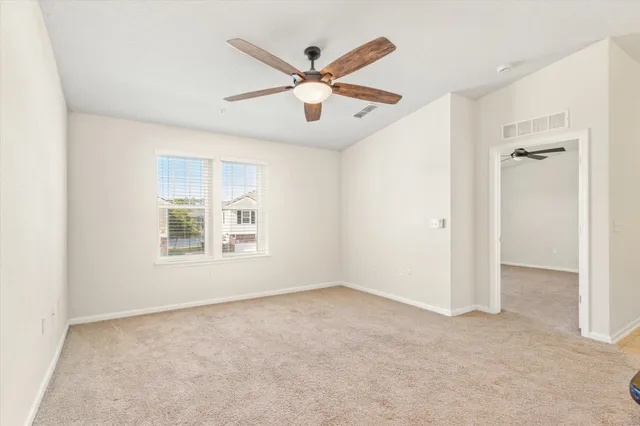 an empty room and chandelier fan in hallway