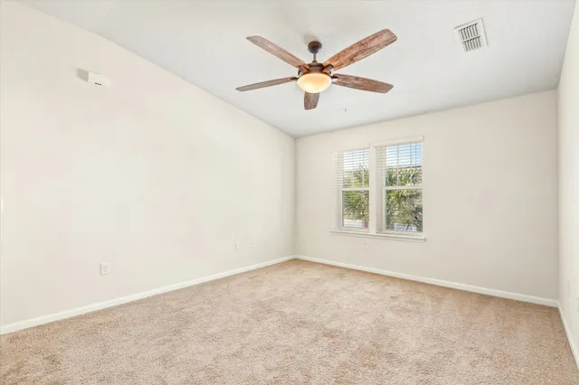 an empty room with ceiling fan and window