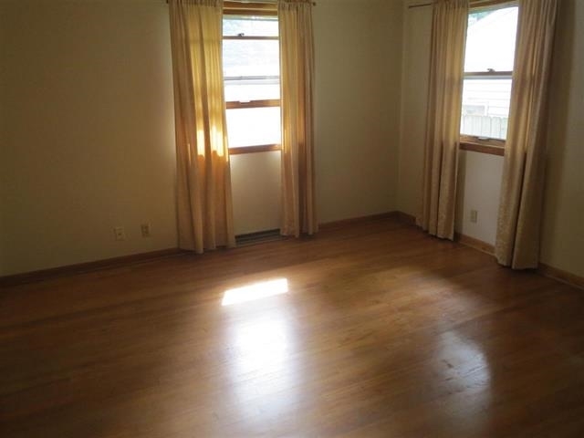 6103 Park Ridge Road Loves Park, IL 61111 - Photo 17 of 22 an empty room with wooden floor and windows with curtains