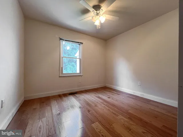 an empty room with wooden floor chandelier fan and windows