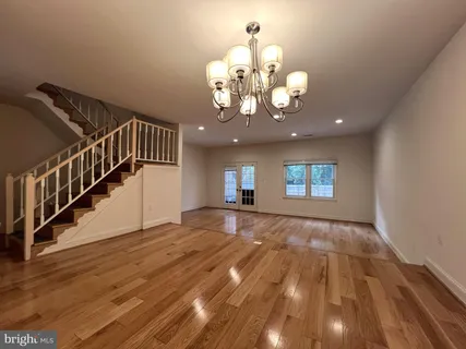 a view of an empty room with wooden floor and a chandelier