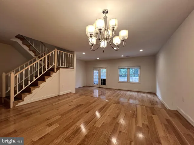 a view of an empty room with wooden floor and a chandelier