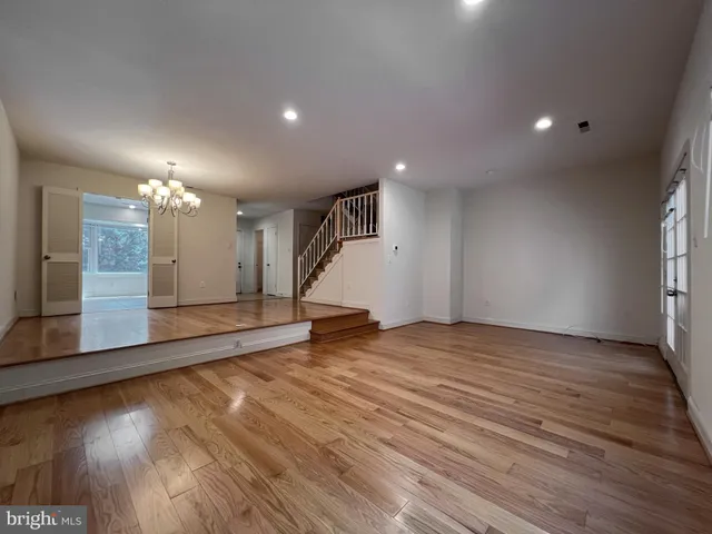 an empty room with wooden floor and kitchen view