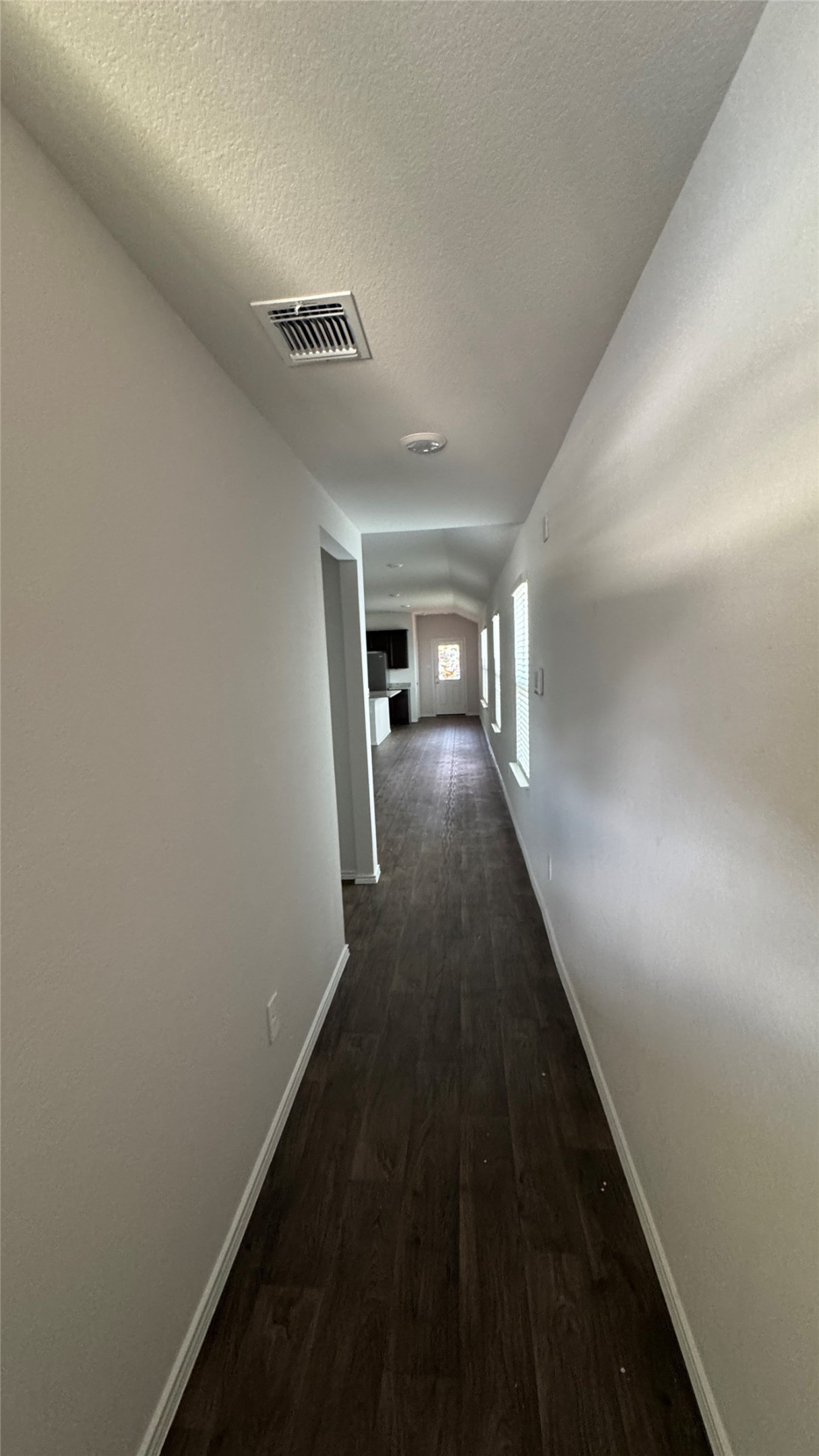 408 Frogmore Loop Kyle, TX 78640 - Photo 28 of 32 Dark wood flooring guides you through this pristine hallway, leading to further living spaces.