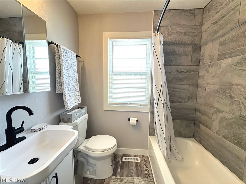 2440 Dentzler Road Parma, OH 44134 - Photo 8 of 11 Bathroom with vanity, shower / tub combo with curtain, and wood finished floors