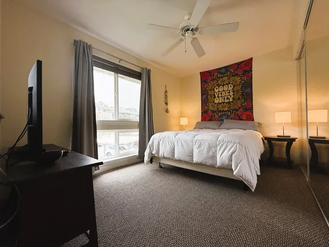 a bedroom with a bed and a flat tv screen next to a window