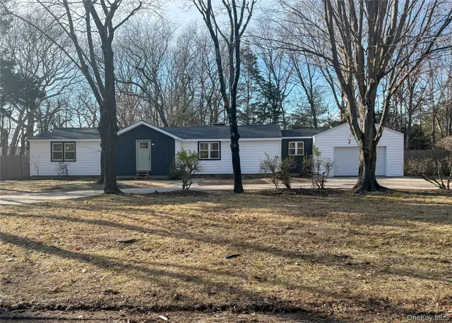 a front view of a house with a dirt yard and a large tree