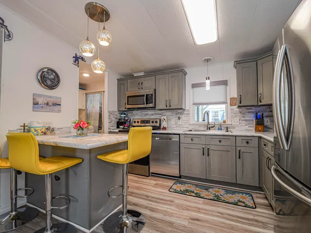 a kitchen with stainless steel appliances granite countertop a refrigerator a stove top oven a sink dishwasher and white cabinets with wooden floor