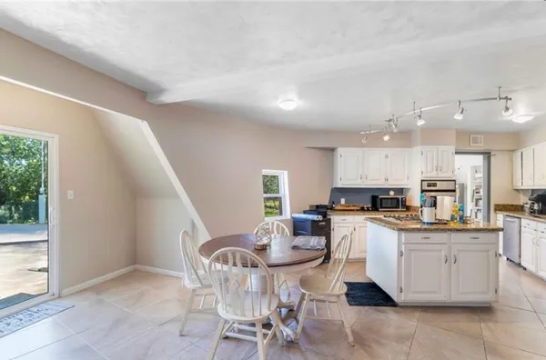 a kitchen with a dining table chairs and white cabinets