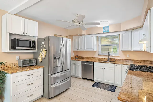 a kitchen with granite countertop a refrigerator stove microwave and cabinets