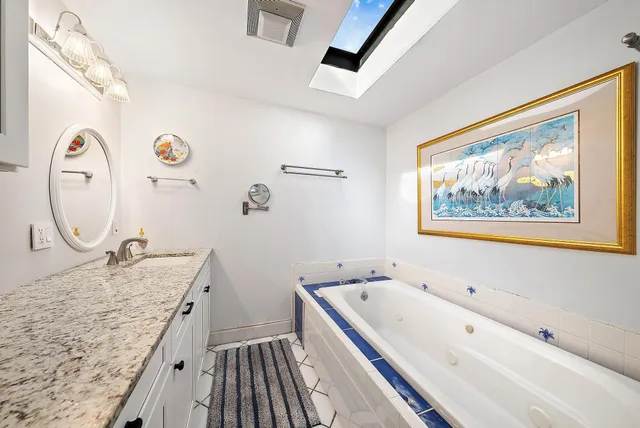 a bathroom with a granite countertop tub sink and mirror