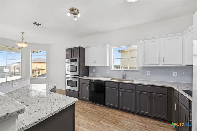 a kitchen with stainless steel appliances granite countertop a refrigerator and a stove top oven