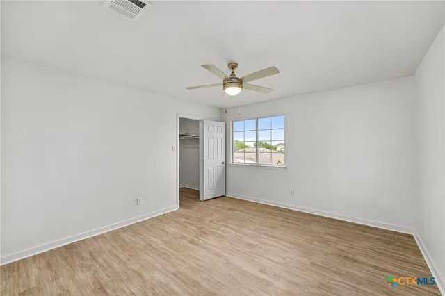 a view of a room with wooden floor and a ceiling fan