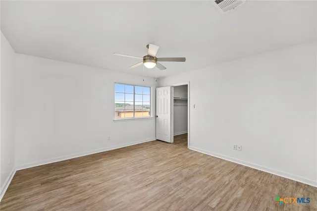 an empty room with wooden floor and ceiling fan