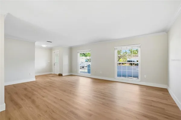 a view of an empty room with wooden floor and a window