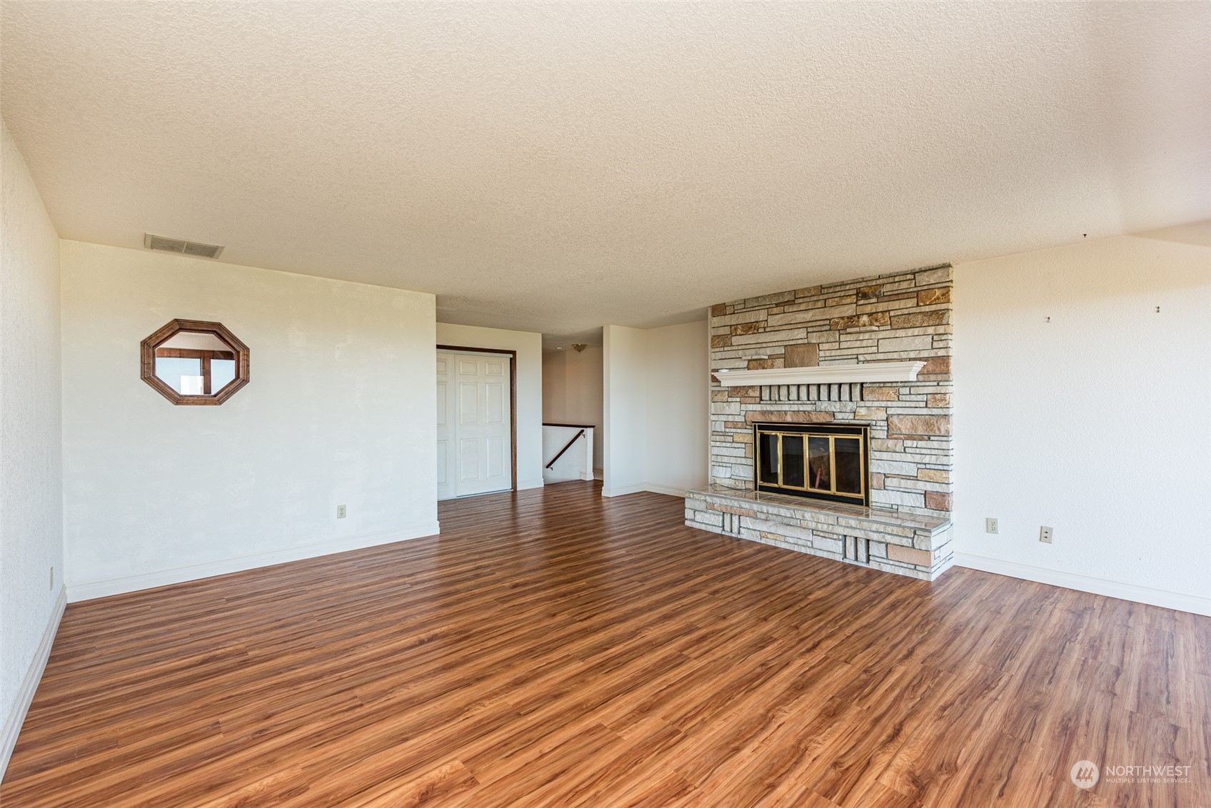 653 Brigadoon Boulevard Sequim, WA 98382 - Photo 6 of 40 an empty room with wooden floor a fireplace and windows
