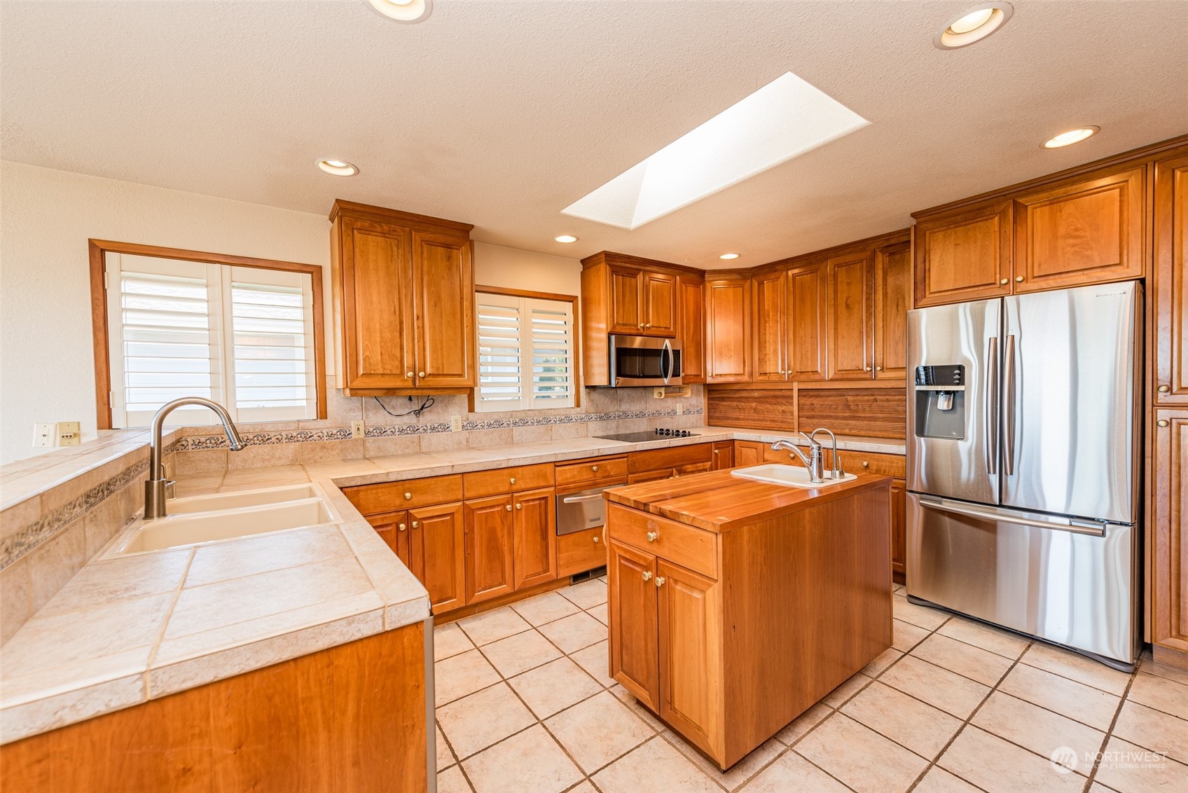653 Brigadoon Boulevard Sequim, WA 98382 - Photo 10 of 40 a kitchen with stainless steel appliances granite countertop a refrigerator a sink dishwasher a stove with white cabinets and wooden floor