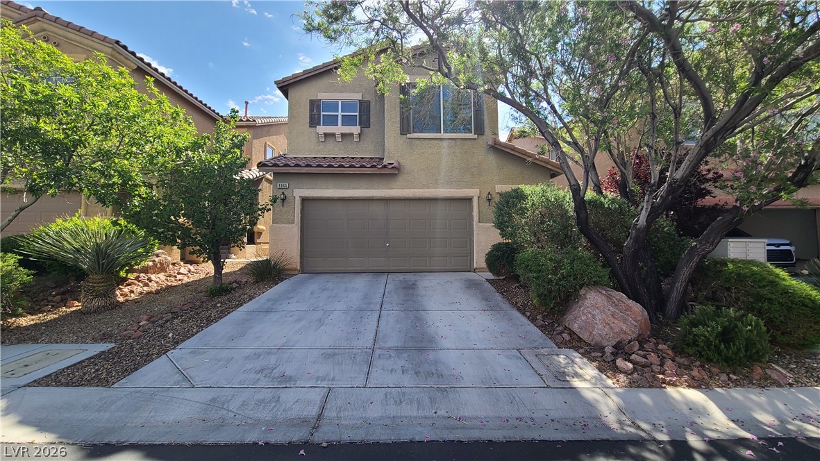 8944 Rutherford Grove Street Las Vegas, NV 89148 - Photo 1 of 35 A welcoming driveway leads to a two-story residence, framed by mature trees and desert-adapted landscaping.