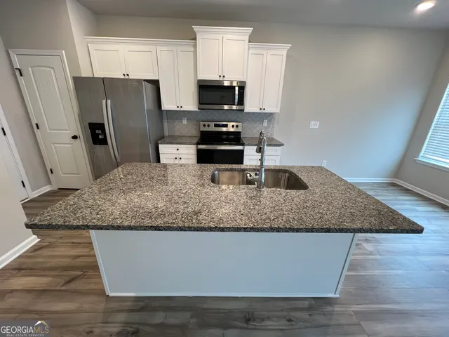 a kitchen with granite countertop a refrigerator and a sink