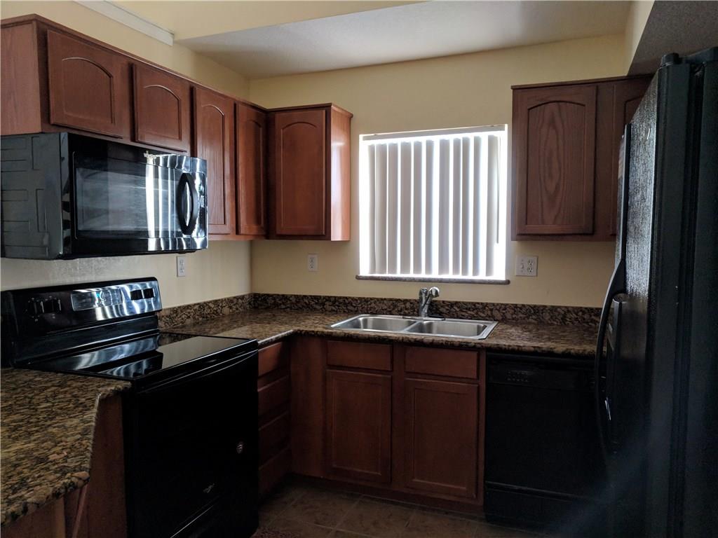 1645 Southeast Pomeroy Street, Unit 42 Stuart, FL 34997 - Photo 7 of 29 a kitchen with granite countertop a sink stove and microwave